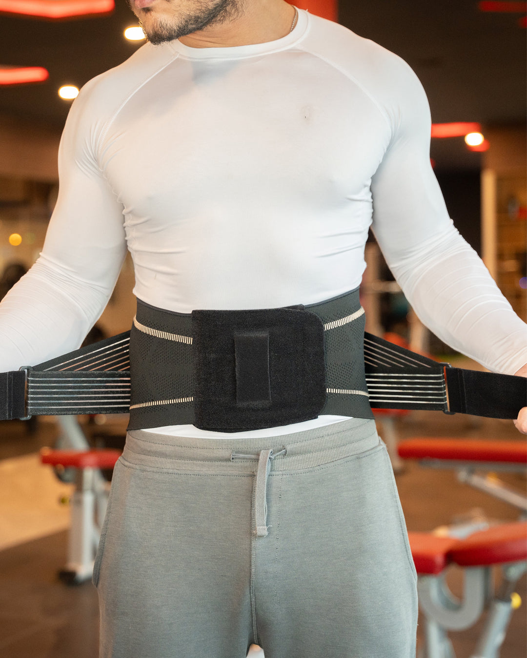 Sea Dragon Dreams copper-infused back support brace with adjustable Velcro straps worn by a man in a gym setting.
