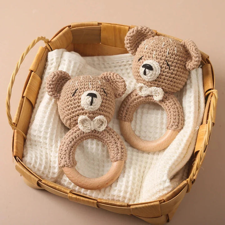 Sea Dragon Dreams crochet bear rattles with wooden teething rings inside a woven basket on a white cloth.