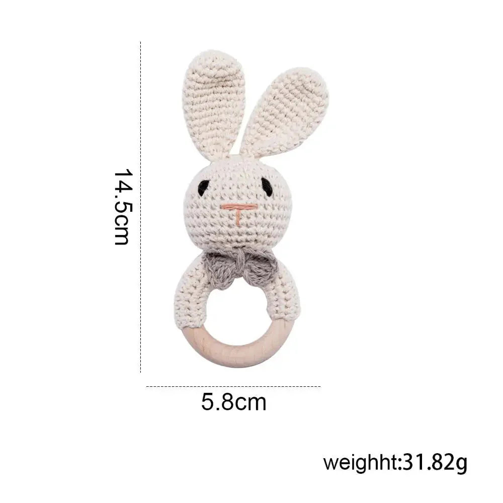 Sea Dragon Dreams crochet bunny rattle with a wooden teether ring, soft beige cotton yarn, and a grey bow tie.