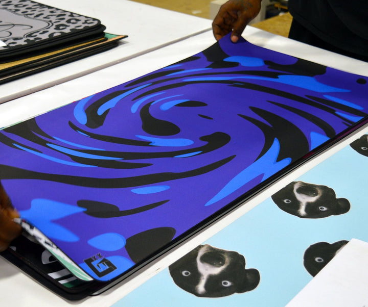 Sea Dragon Dreams custom XL desk mat with a blue and black swirl design being inspected on a production table.