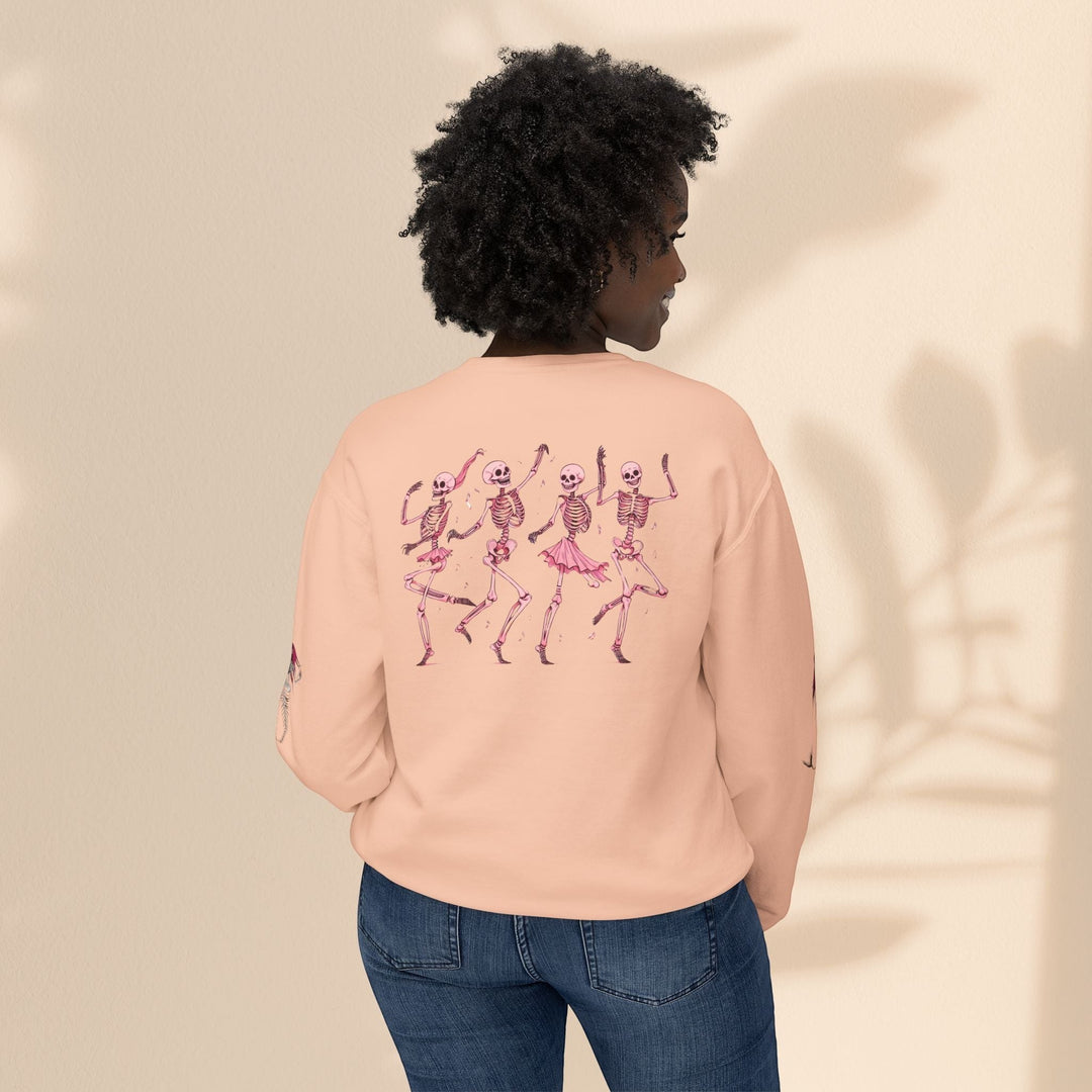 Sea Dragon Dreams peach crewneck sweatshirt with dancing skeletons graphic on back worn by a woman with curly hair