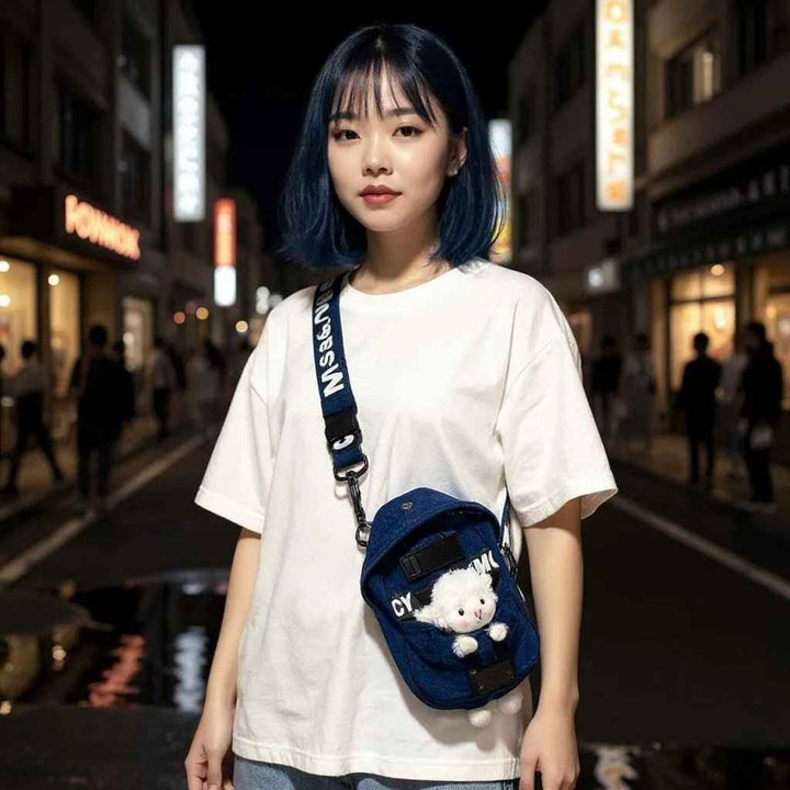 Sea Dragon Dreams kawaii denim crossbody sling bag with a cute sheep charm worn by a woman on a city street at night.