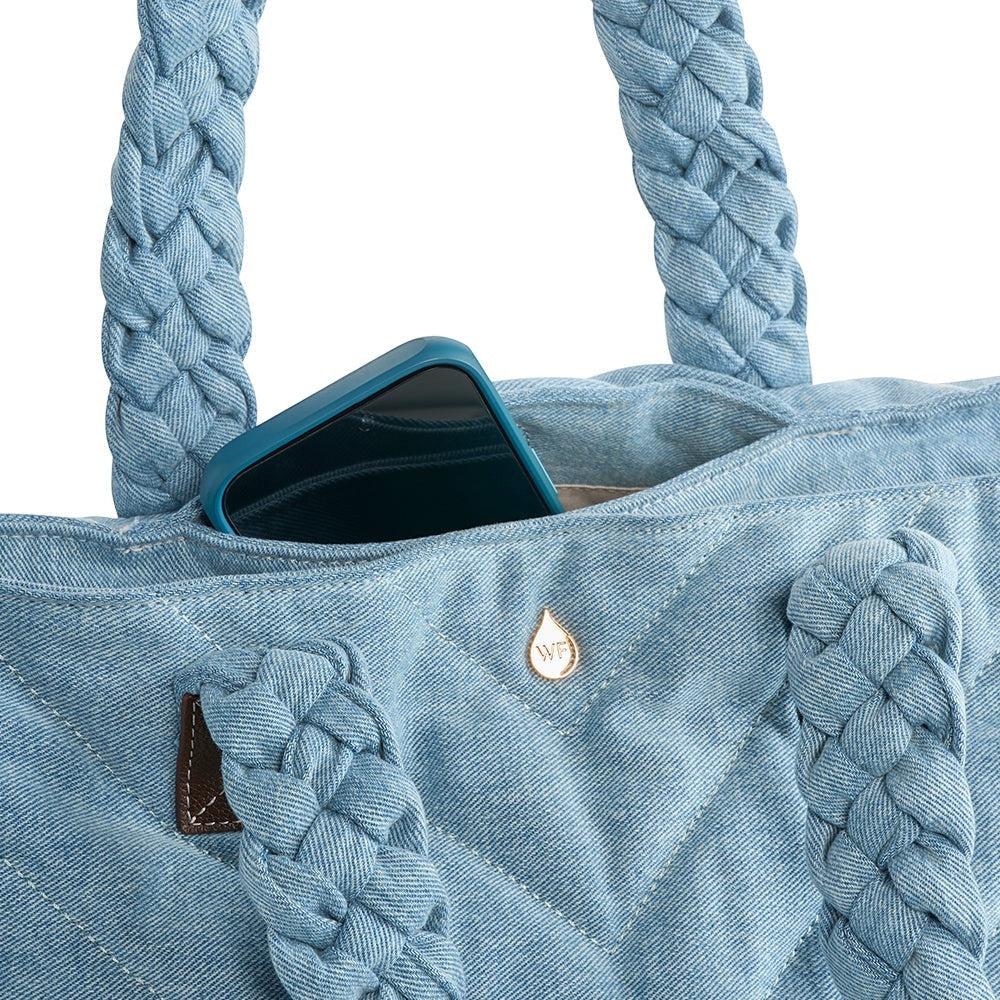 Sea Dragon Dreams denim quilted HydroTote bag with braided handles and a phone tucked into an exterior pocket