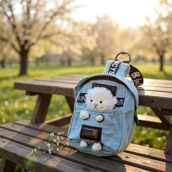 Sea Dragon Dreams kawaii denim crossbody sling bag with a cute sheep charm sitting on a wooden park bench.