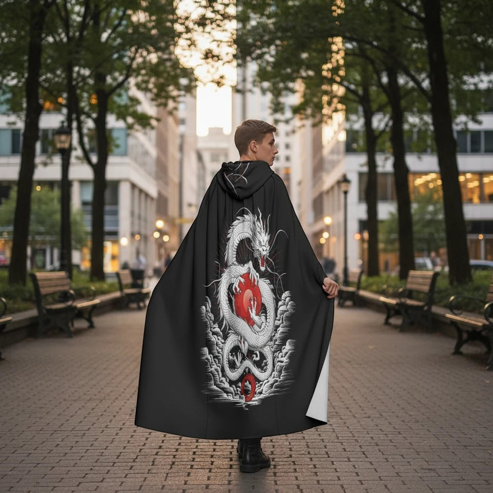 Sea Dragon Dreams unisex hooded cloak featuring a white dragon and red orb print on black scuba fabric in a city park.
