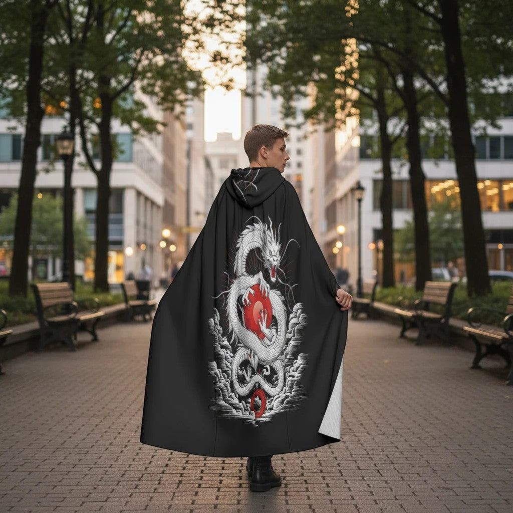 Sea Dragon Dreams unisex hooded cloak featuring a white dragon and red orb print on black scuba fabric in a city park.