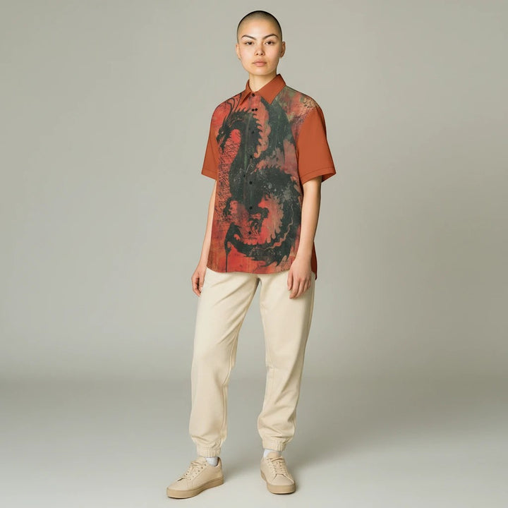 Model wearing a Sea Dragon Dreams collared shirt with a bold black dragon print on a rust-red cotton poplin fabric.