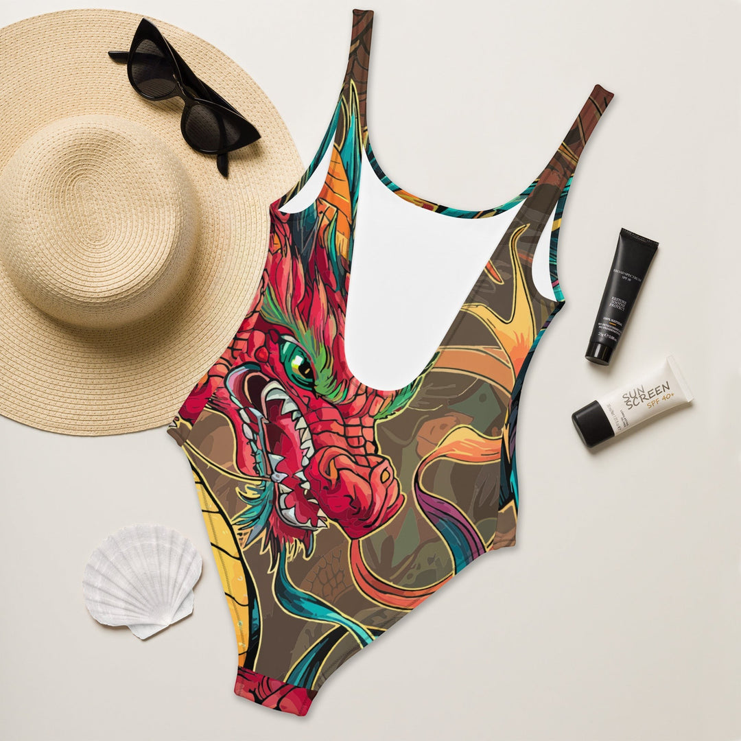 Sea Dragon Dreams one-piece swimsuit with a vibrant red dragon print, scoop neck, and cheeky fit on a beach background.