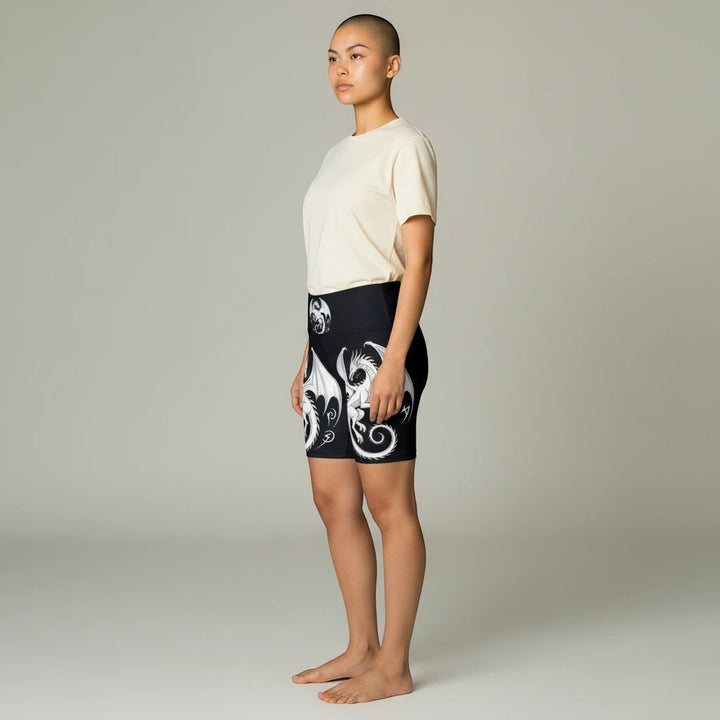 Sea Dragon Dreams women's athletic shorts with white dragon print on black polyester fabric, side view on model.