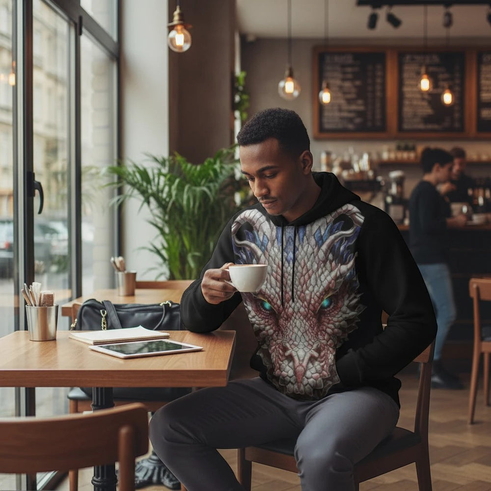 Sea Dragon Dreams men's black pullover hoodie featuring a detailed dragon face graphic, worn by a man in a cafe.