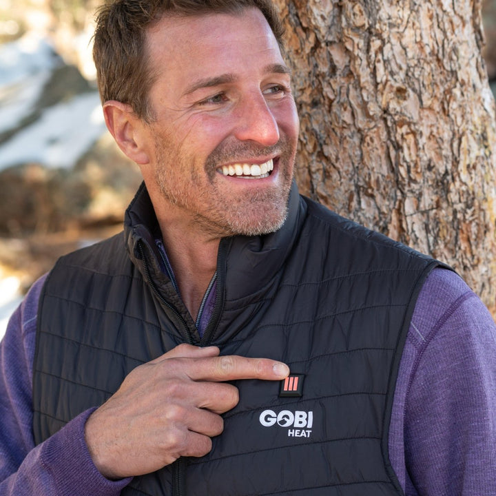 Sea Dragon Dreams Dune men's black heated vest with adjustable heat settings worn by a smiling man outdoors