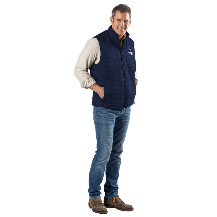 Man wearing a navy blue Sea Dragon Dreams Dune heated vest over a beige shirt and jeans, standing against a white background.