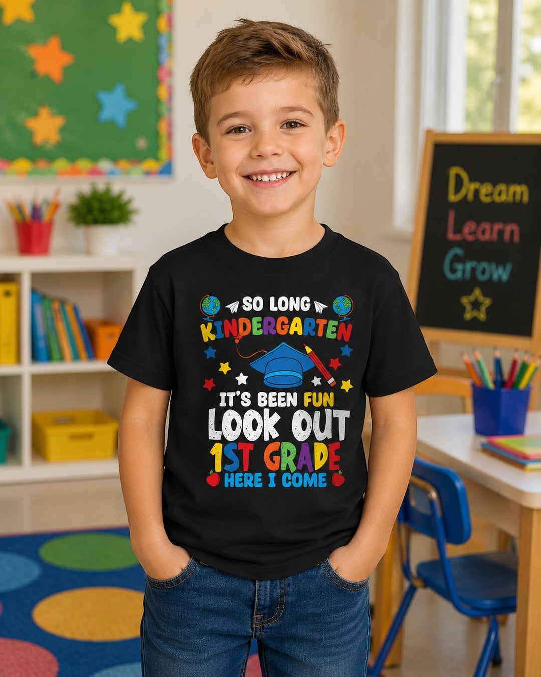 Sea Dragon Dreams black youth t-shirt with colorful Look Out First Grade graphic worn by a smiling boy in a classroom