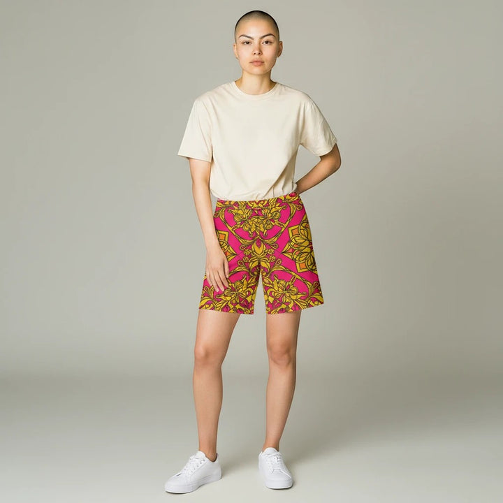 Sea Dragon Dreams women's bike shorts in pink and gold floral print, worn with a beige t-shirt and white sneakers.