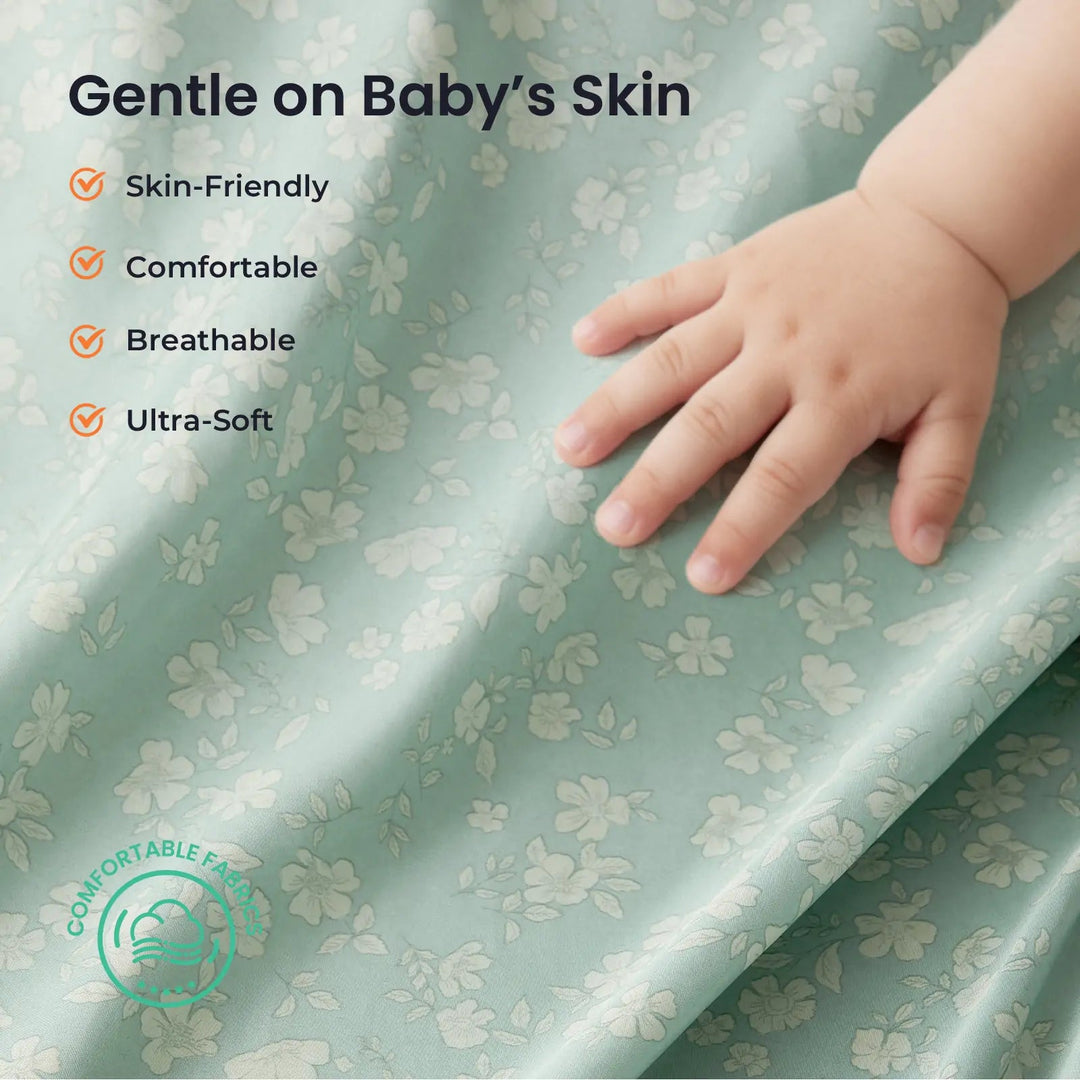 Sea Dragon Dreams soft sage green floral polyester fabric being touched by a baby hand, highlighting skin-friendly feel.