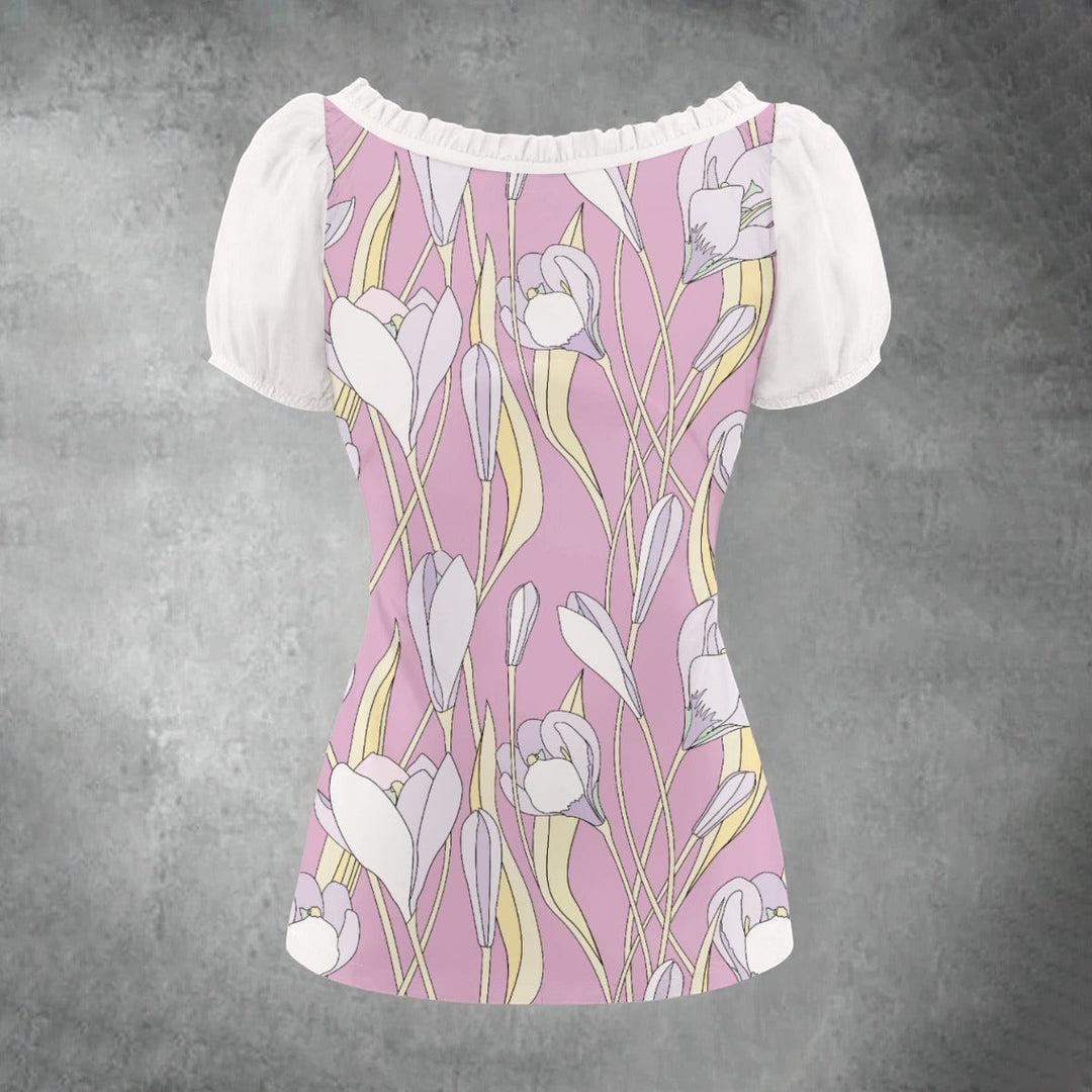 Sea Dragon Dreams floral puff-sleeve blouse with a pink background and white pleated details on a grey background.