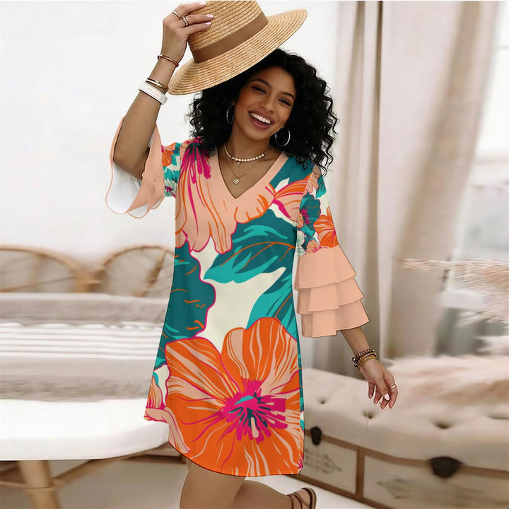 A woman wearing a Sea Dragon Dreams floral V-neck dress with stacked ruffle sleeves and a straw hat in a bright room.