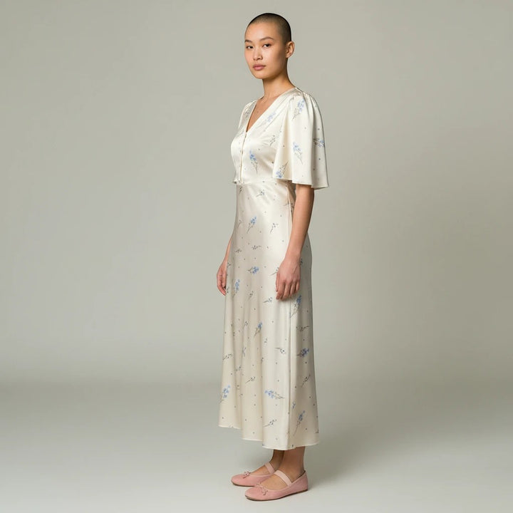 Sea Dragon Dreams cream satin maxi dress with blue floral print, V-neckline, and short sleeves on a model