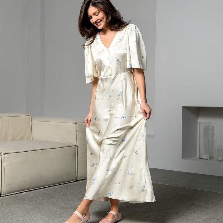 Sea Dragon Dreams cream satin maxi dress with blue floral print, V-neckline, and short flutter sleeves on a model