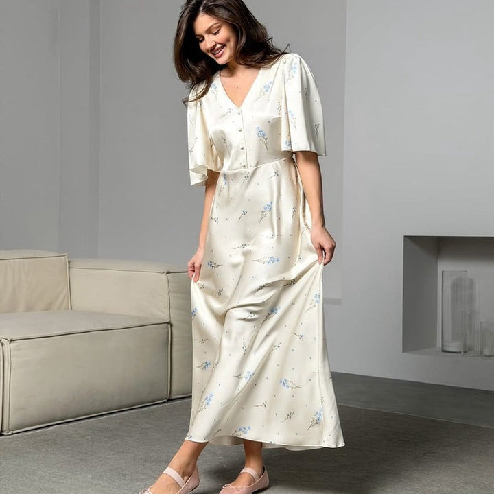 Sea Dragon Dreams cream satin maxi dress with blue floral print, V-neckline, and short flutter sleeves on a model