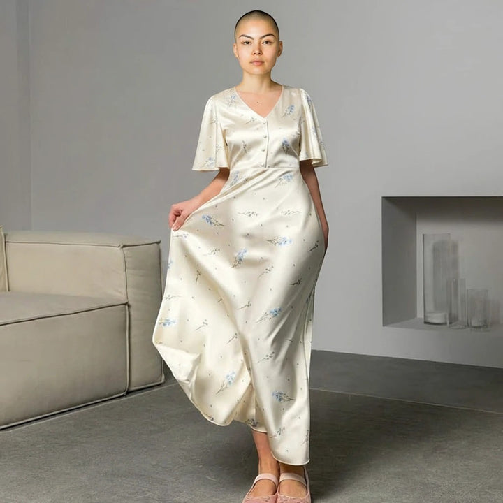 Sea Dragon Dreams cream satin maxi dress with blue floral print, V-neck, and short sleeves worn by a model