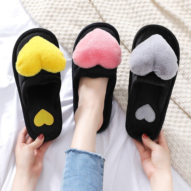 Sea Dragon Dreams fluffy heart slippers in black with yellow, pink, and grey plush heart accents on a white blanket