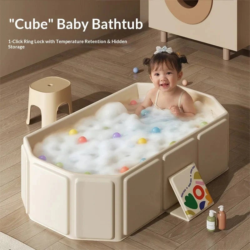 Sea Dragon Dreams foldable baby bathtub in beige with a smiling toddler playing in soapy water and colorful balls