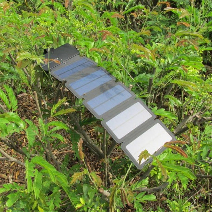 Sea Dragon Dreams portable folding solar panel charger resting on green outdoor foliage for camping and hiking