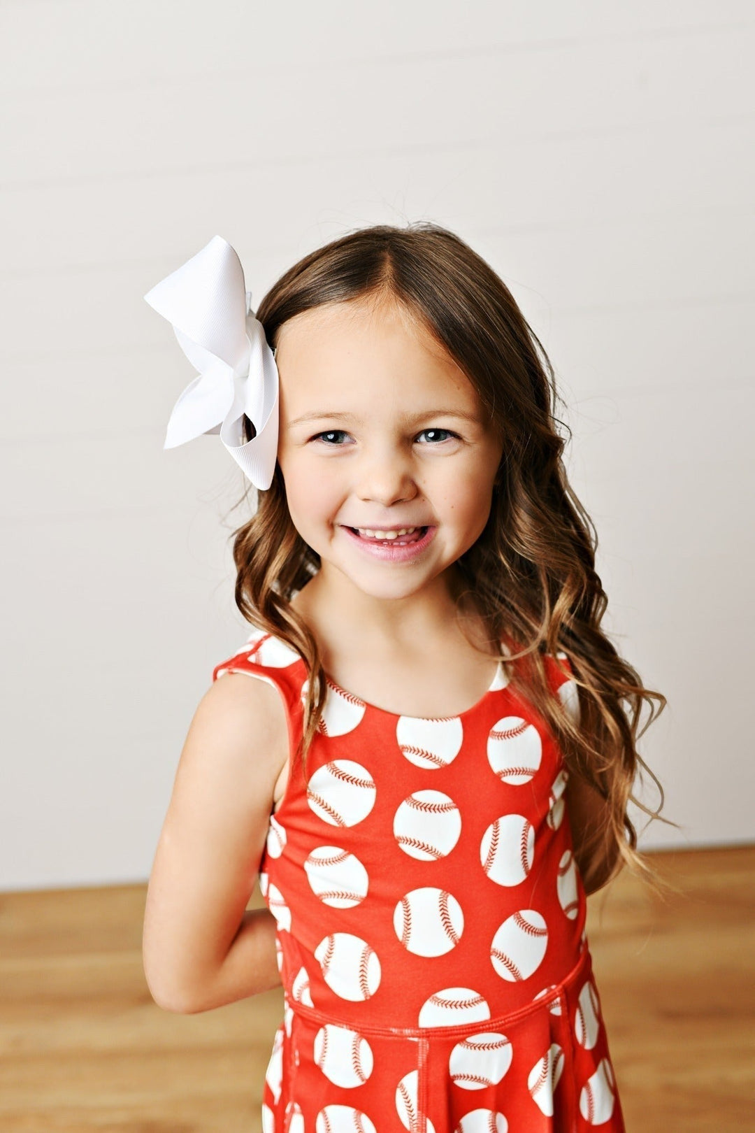 Sea Dragon Dreams girls baseball print athletic twirl dress in red with white baseballs and a large white hair bow