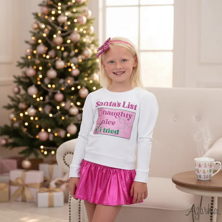 Sea Dragon Dreams white long-sleeve sweatshirt with Santa's List graphic, worn by a girl with a pink skirt and headband