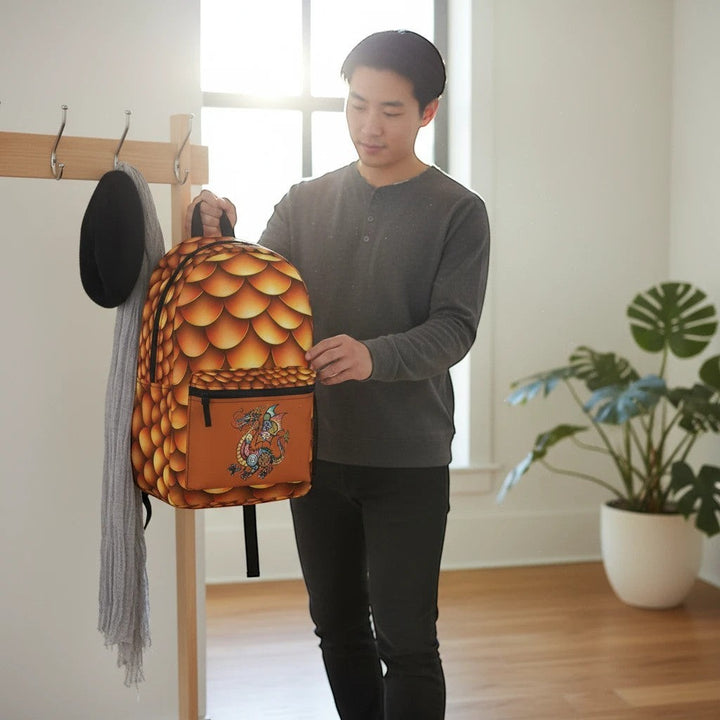 A man holding a Sea Dragon Dreams backpack with a golden dragon scale pattern and a small dragon graphic on the front.