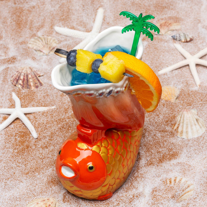 Sea Dragon Dreams Goldfish Tiki Mug filled with a blue tropical cocktail, garnished with pineapple and orange slices.