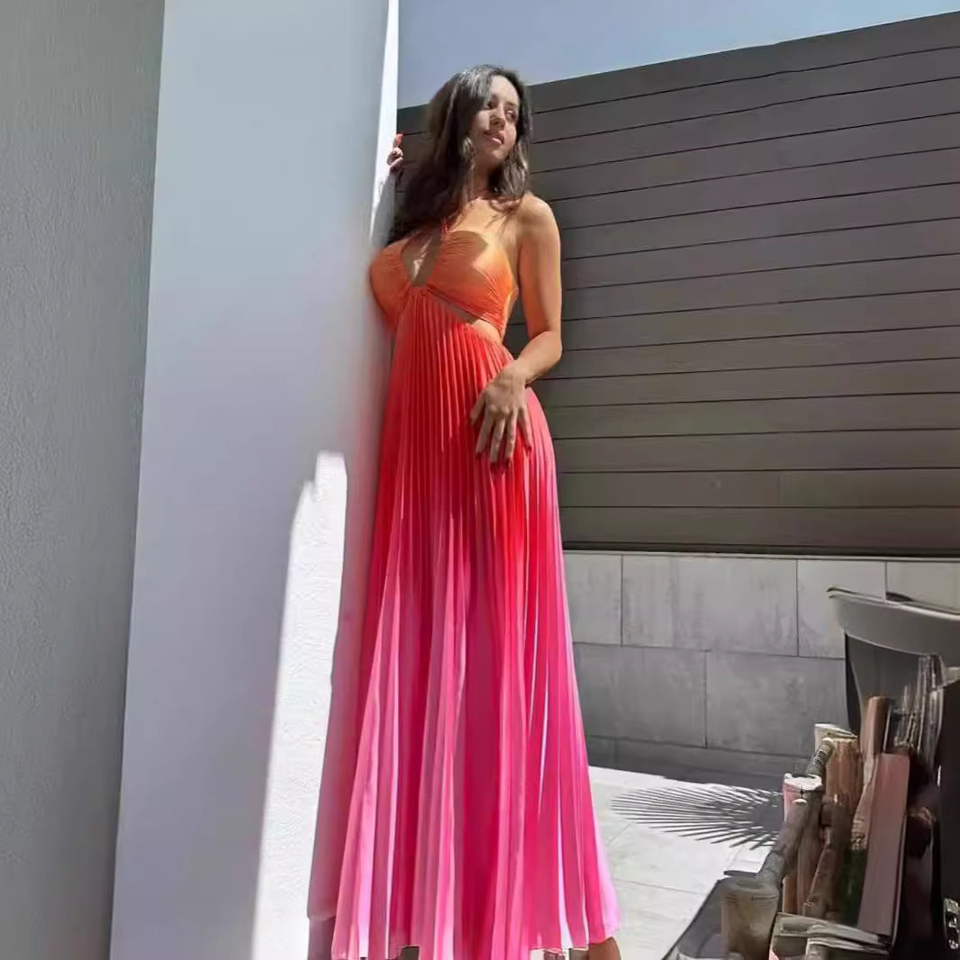 Sea Dragon Dreams gradient orange and pink pleated halter maxi dress worn by a woman leaning against a wall