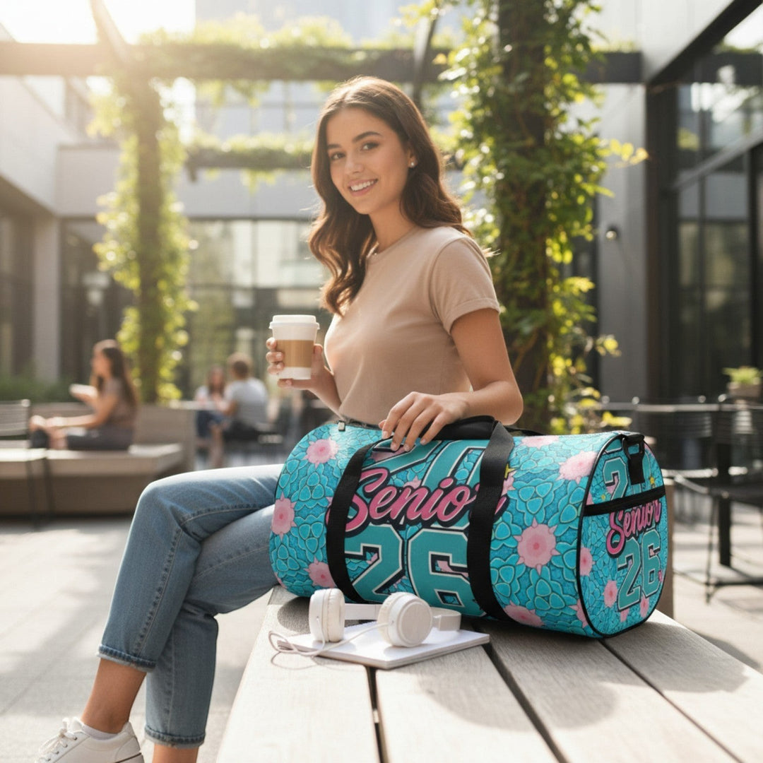 Sea Dragon Dreams 2026 Graduate duffel bag with blue floral pattern, held by a smiling woman on a park bench.