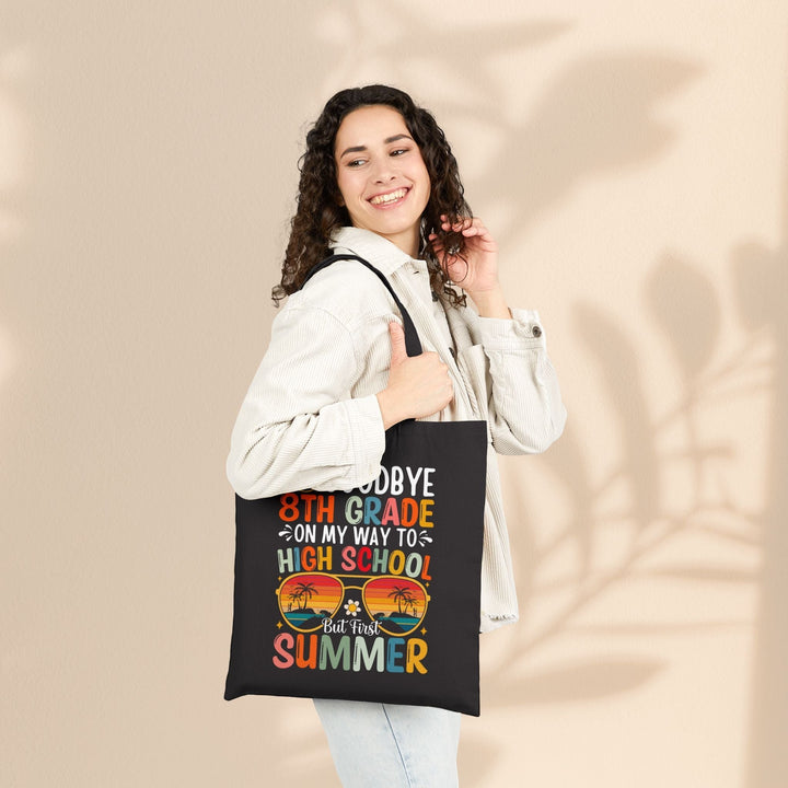 Sea Dragon Dreams black cotton canvas tote bag with graduation themed graphic worn by a smiling woman.