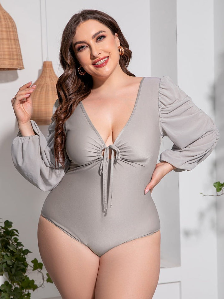 Sea Dragon Dreams plus size grey one-piece swimsuit with deep V-neck, tie front, and long balloon sleeves.