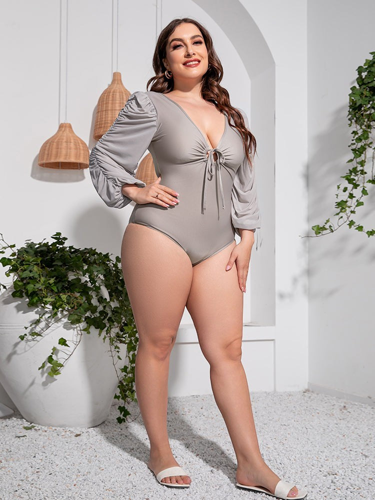 Sea Dragon Dreams plus size grey one-piece swimsuit with deep V-neck, tie front, and long balloon sleeves.