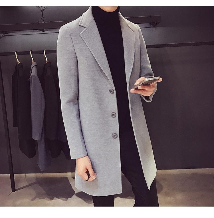 Sea Dragon Dreams men's light grey cotton trench coat with a turn-down collar worn over a black turtleneck sweater.