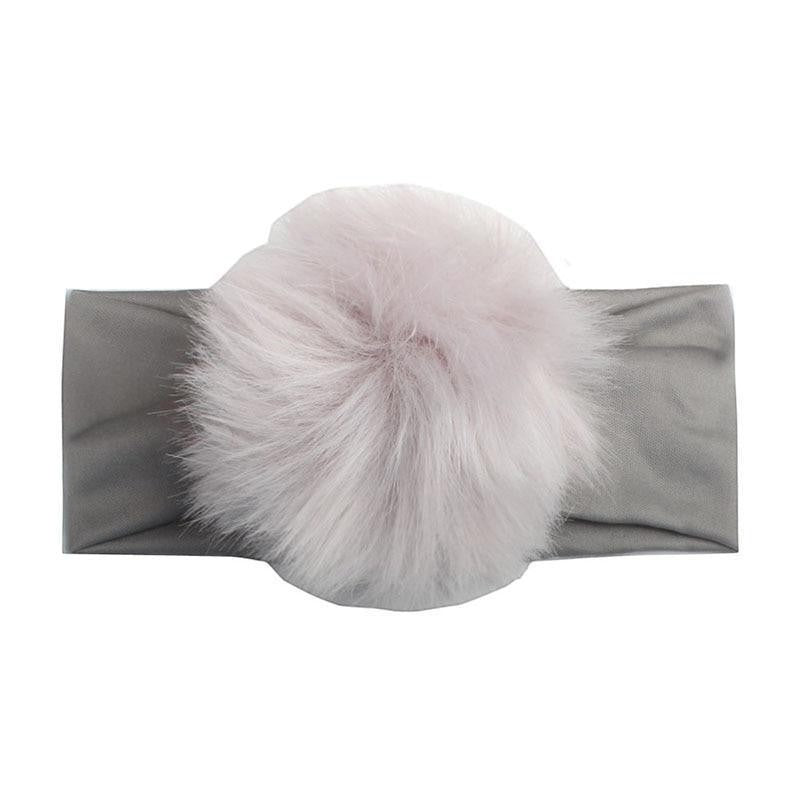 Sea Dragon Dreams handmade baby headband featuring a soft grey elastic band and a fluffy light pink faux fur pom-pom.