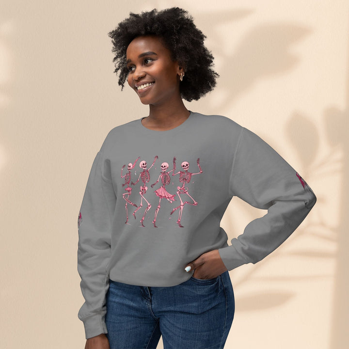 Sea Dragon Dreams grey crewneck sweatshirt featuring pink dancing skeletons, worn by a smiling woman in jeans.