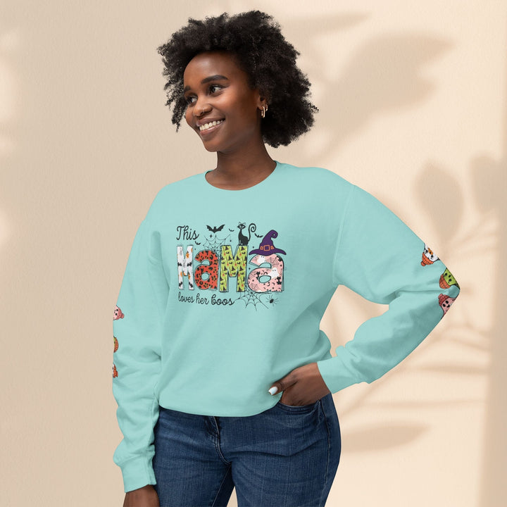 Sea Dragon Dreams light blue crewneck sweatshirt with This Mama Loves Her Boos Halloween print on a smiling woman.