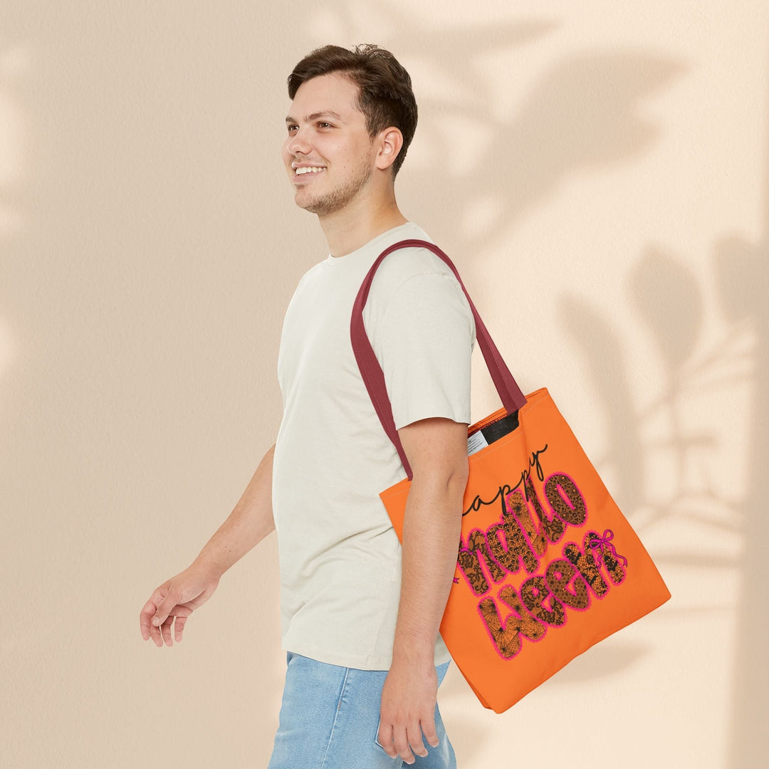 Sea Dragon Dreams Happy Halloween tote bag in orange with maroon handles carried by a man in a beige t-shirt.