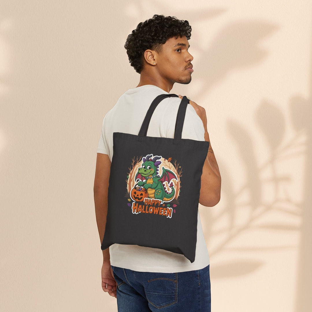 Sea Dragon Dreams black cotton canvas tote bag with a cute dragon holding a pumpkin, worn over the shoulder by a man.