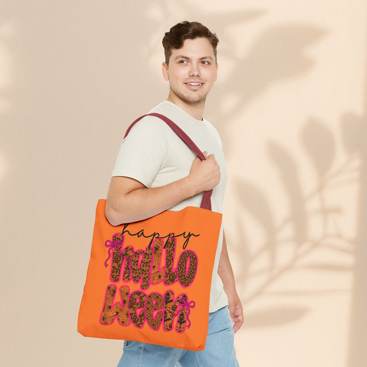 Man carrying a Sea Dragon Dreams orange Happy Halloween tote bag with leopard print lettering and maroon handles.