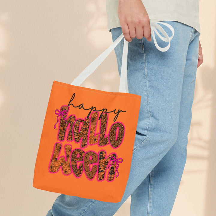 Sea Dragon Dreams orange polyester tote bag with Happy Halloween text, held by a person wearing jeans.