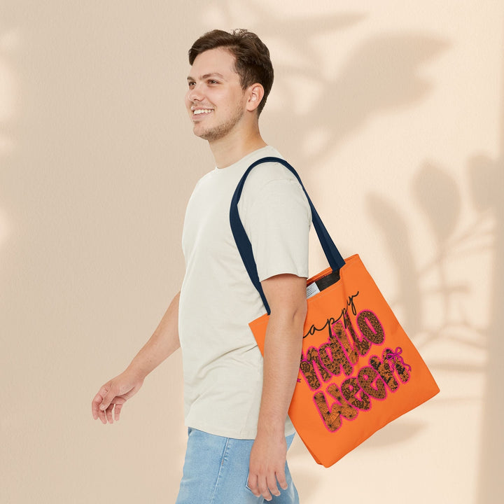 Sea Dragon Dreams Happy Halloween tote bag in orange with dark handles, carried by a man in a beige t-shirt.
