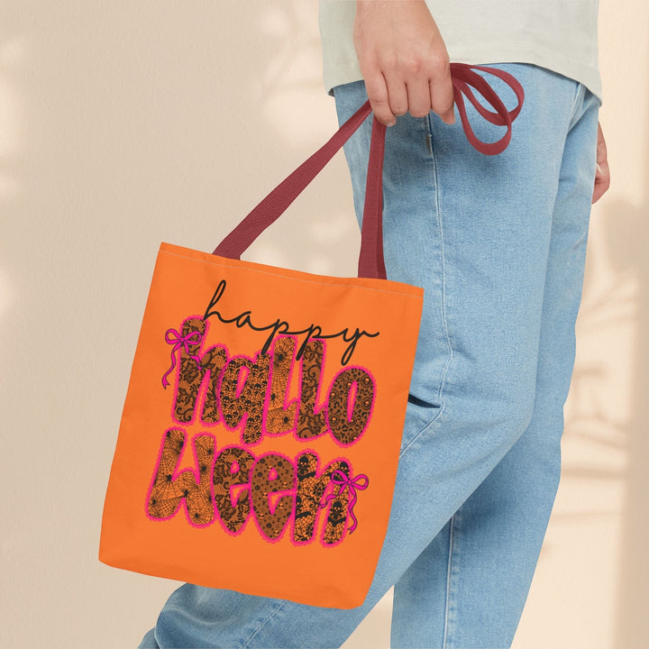 Sea Dragon Dreams orange polyester tote bag with Happy Halloween leopard print text and pink bows held by a person.