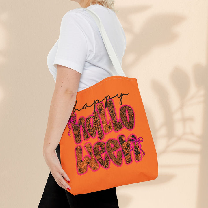 Sea Dragon Dreams reusable orange polyester tote bag with Happy Halloween text, worn over the shoulder by a woman.