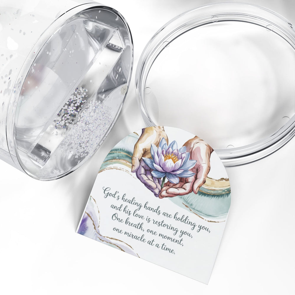 Sea Dragon Dreams inspirational snow globe featuring a lotus flower in hands with a healing message on a white surface