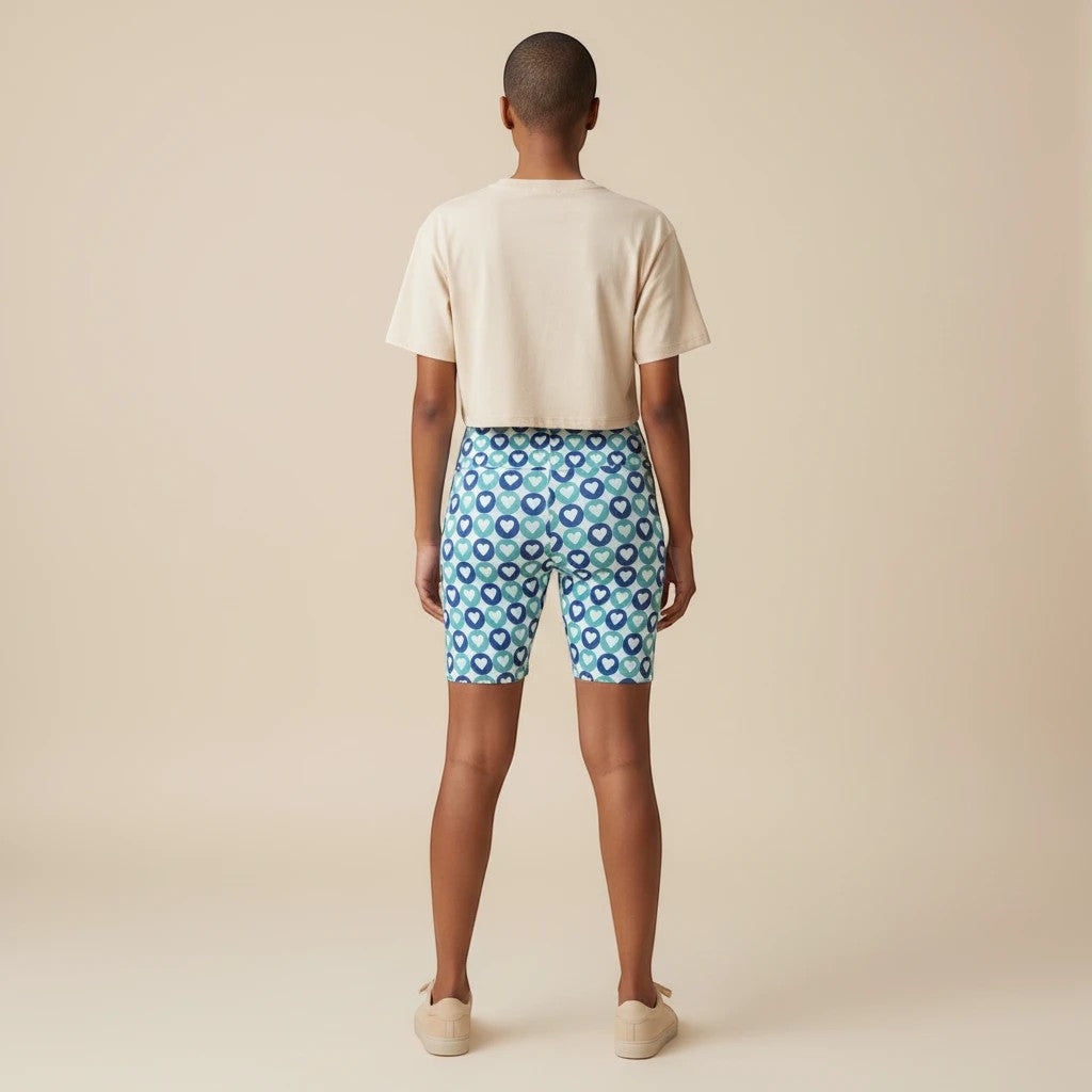 Sea Dragon Dreams women's workout shorts featuring a blue heart pattern, worn with a beige crop top, back view.